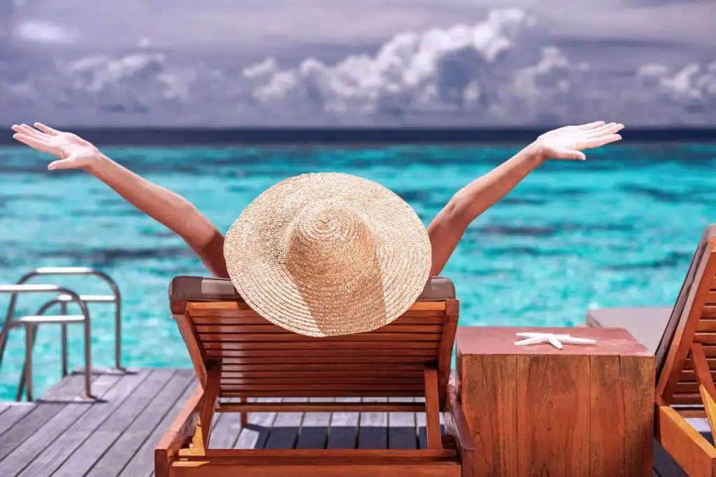 a woman stretching her arms as she lounges on an oceanside deck